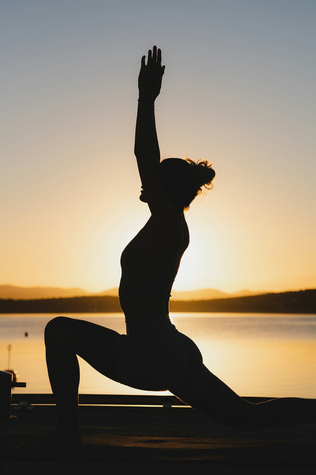 a-woman-doing-a-yoga-pose-in-front-of-a-body-of-water-nbx2vppn64k